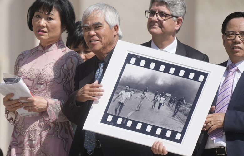 Pulitzer Prize-winning photographer Nick Ut, center, flanked by Kim Phuc, holds the” Napalm Girl”, his Pulitzer Prize winning photo as they wait to meet with Pope Francis during the weekly general audience in St. Peter’s Square at The Vatican, Wednesday, May 11, 2022. Ut and UNESCO Ambassador Kim Phuc are in Italy to promote the photo exhibition “From Hell to Hollywood” resuming Ut’s 51 years of work at the Associated Press, including the 1973 Pulitzer-winning photo of Kim Phuc fleeing her village after it was accidentally hit by napalm bombs dropped by South Vietnamese forces. (AP Photo/Gregorio Borgia) GB110 GB110