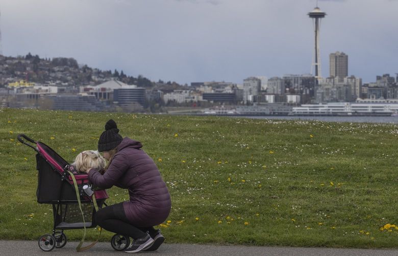 Under cloudy but rainless skies, a woman pauses during a walk to chat with her dog while taking a walk along the waterfront in West Seattle Monday, April 11, 2022. Rain is predicted for Tuesday but the rest of the week should be sunny.
220095
