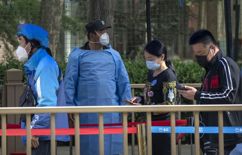 People wearing face masks stand in line at a coronavirus testing site in Beijing, Thursday, May 12, 2022. (AP Photo/Mark Schiefelbein) XMAS106 XMAS106
