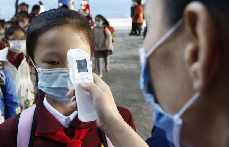 FILE – A teacher takes the body temperature of a schoolgirl to help curb the spread of the coronavirus before entering Kim Song Ju Primary School in Central District in Pyongyang, North Korea, Wednesday, Oct. 13, 2021. Before acknowledging domestic COVID-19 cases, Thursday, May 12, 2022, North Korea spent 2 1/2 years rejecting outside offers of vaccines and steadfastly claiming that its superior socialist system was protecting its 26 million people from â€œa malicious virusâ€ that had killed millions around the world. (AP Photo/Cha Song Ho, File) BKWS311 BKWS311