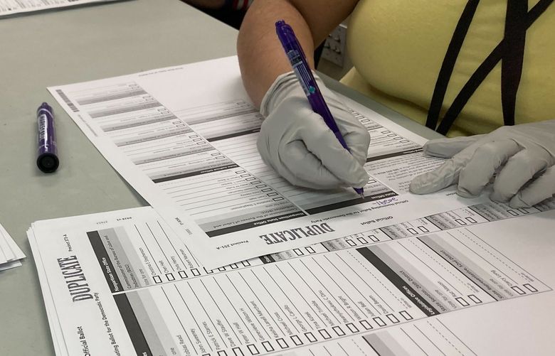 Workers check ballots at elections offices in Clackamas County, Oregon, the state’s third most populous county south of Portland, Tuesday, May 17, 2022. Many ballots in the county were printed with blurry barcodes, preventing them from being read by voting tabulation machines. Workers, one Democrat and one Republican per pair, are re-recording votes from the blurred ballots on new ballots so they can be read. The problem may cause significant delays in vote-counting in a county that includes parts of two Congressional districts, including one with a competitive Democratic primary. (AP Photo/Gillian Flaccus) LA205 LA205