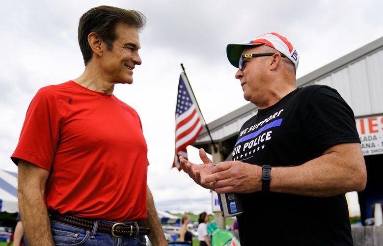 FILE – Mehmet Oz, a Republican candidate for U.S. Senate in Pennsylvania, meets with an attendee during a visits to a car show in Carlisle, Pa., May 14, 2022. (AP Photo/Matt Rourke) WX203 WX203