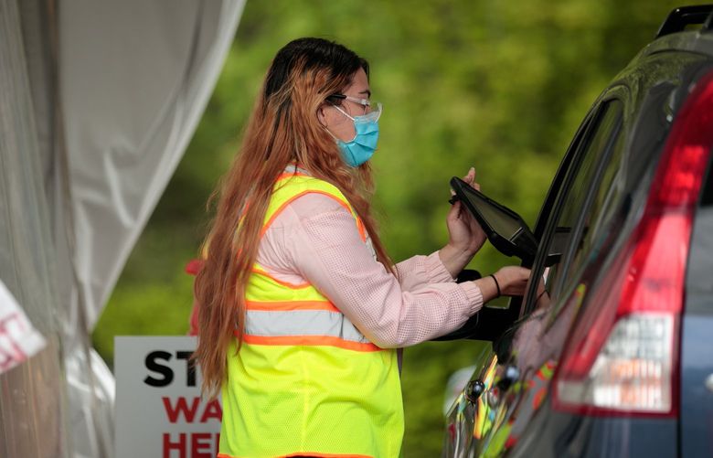 Irma Placencia, checks in patients at Public Health – Seattle & King County testing site in Federal Way, at the Federal Way Aquatics Center Tuesday, May 17, 2022. The site is administered in partnership with Virginia Mason Franciscan Health system. 220417