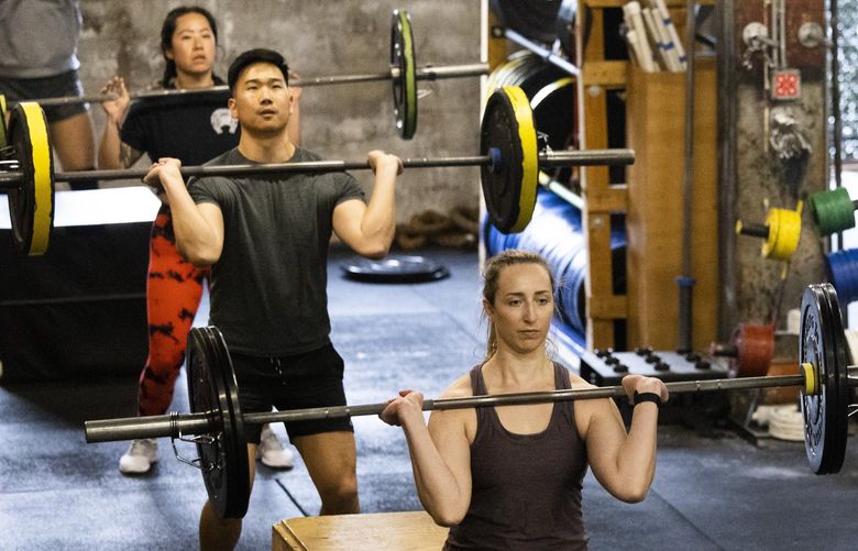 Class participants lift weights in unison as they workout at Foundation CrossFit in Seattle May 13, 2022.