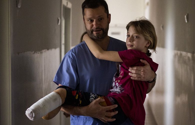 Yana Stepanenko, 11, is carried by a doctor at a public hospital in Lviv, Ukraine, Friday, May 13, 2022. Yana and her mother Natasha, 43, were injured April 8 during shelling at the train station of the eastern city of Kramatorsk where they travelled with Yana’s twin brother Yarik from their village near the front line. They were planning to catch an evacuation train heading west and, they hoped, to safety. (AP Photo/Emilio Morenatti) XEM501 XEM501