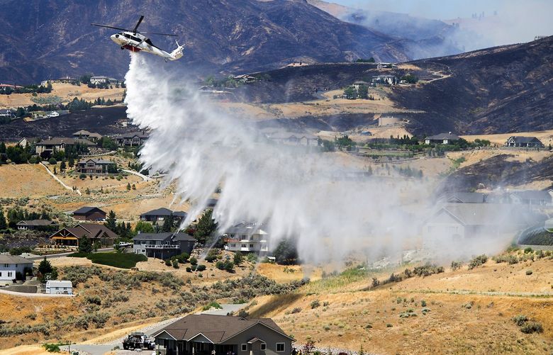 A helicopter makes a drop over houses along Sky Crest Lane before firefighters begin a burnout at the Red Apple Fire on Wednesday, July 14, 2021.