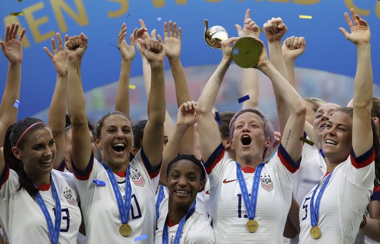 FILE – United States’ Megan Rapinoe lifts up the trophy after winning the Women’s World Cup final soccer match between US and The Netherlands at the Stade de Lyon in Decines, outside Lyon, France, in July 7, 2019. The U.S. Soccer Federation reached milestone agreements to pay its men’s and women’s teams equally, making the American national governing body the first in the sport to promise both sexes matching money. (AP Photo/Alessandra Tarantino, File) NYDD202 NYDD202