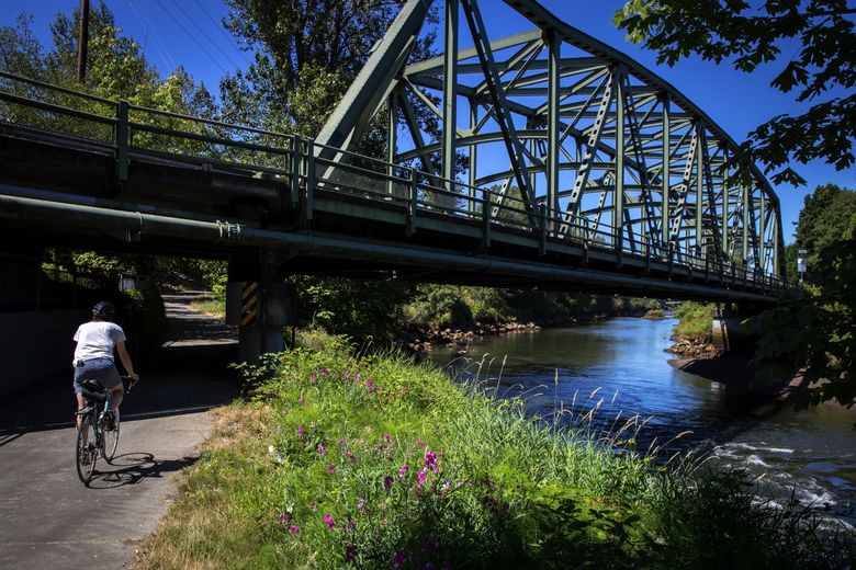 A cyclist crosses under the Allentown Bridge along the Duwamish river in Tukwila on the Green River Trail last summer. The trail runs from Seattle to Kent along the Green and Duwamish rivers. King County wants to raise property taxes to fund the preservation of forests, farmland, trails and rivers. (Bettina Hansen / The Seattle Times, file)
