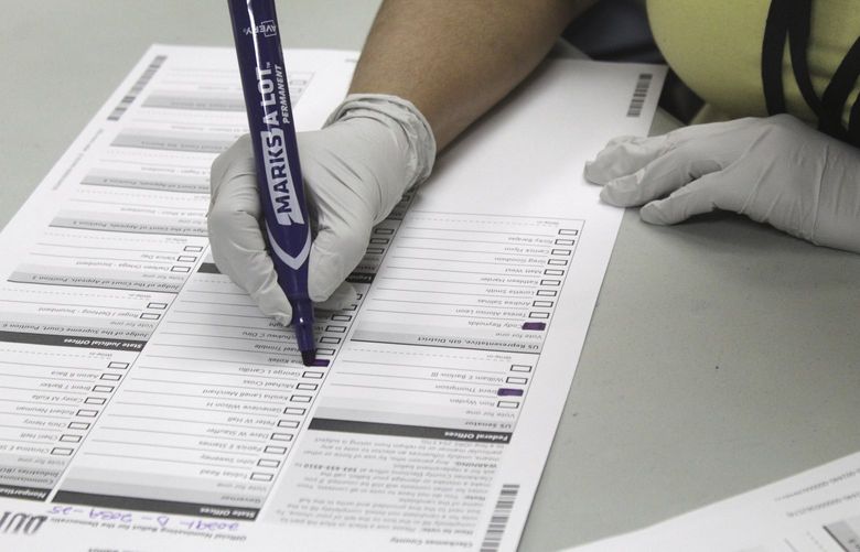 An election worker transfers a ballot from one with a blurry barcode to a new one at the Clackamas County Elections office on Wednesday, May 18, 2022, Oregon City, Ore. Ballots with blurry barcodes that can’t be read by vote-counting machines will delay election results by weeks in a key U.S. House race in Oregon’s primary. (AP Photo/Gillian Flaccus) NYAG205 NYAG205