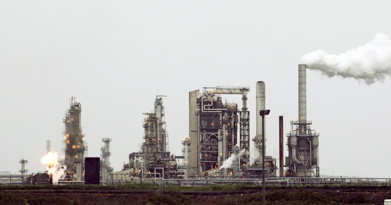 A refinery owned by Andeavor, formerly Tesoro, includes a gas flare flame that is part of normal plant operations, in Anacortes in 2010. Oil refineries are among the entities required to participate in the state’s cap-and-invest program. (Ted S. Warren / The Associated Press)