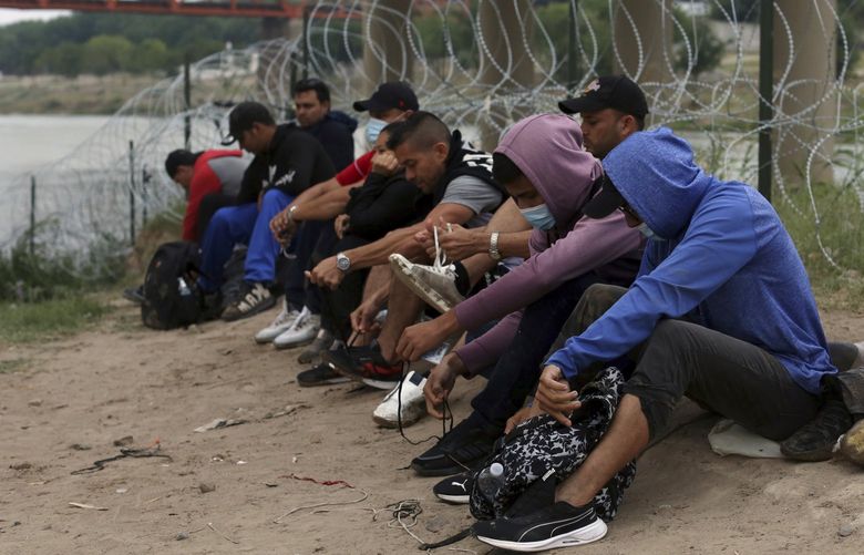 Migrants who had crossed the Rio Grande river into the U.S., remove their shoelaces and others personal items while under custody of National Guard members as they await the arrival of U.S. Border Patrol agents in Eagle Pass, Texas, Friday, May 20, 2022. As U.S. officials anxiously waited, many of the migrants crossing the border from Mexico on Friday were oblivious to a pending momentous court ruling on whether to maintain pandemic-related powers that deny a chance to seek asylum on grounds of preventing the spread of COVID-19. (AP Photo/Dario Lopez-Mills) EPDL113 EPDL113