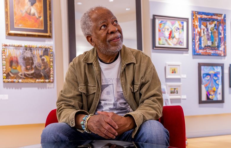 Earnest Thomas, president of the Onyx Fine Arts Collective, sits in front of art at Gallery Onyx in Pacific Place on May 13, 2022.