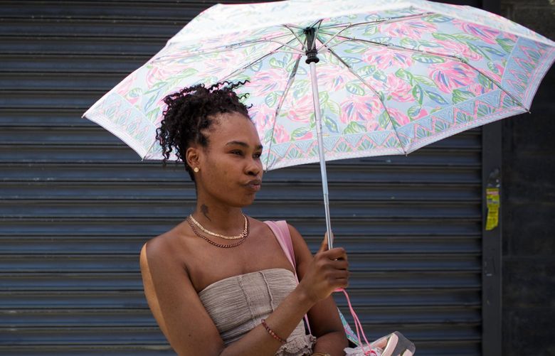 Taesha Nelson uses an umbrella for shade in the Flatbush neighborhood of Brooklyn on Saturday, May 21, 2022. In much of the country, it feels like midsummer this weekend, with high temperatures that may break records. And it’s not even Memorial Day. (Anna Watts/The New York Times) XNYT80 XNYT80