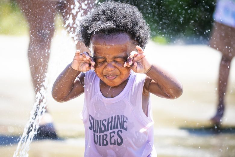 Noah Matondo, 16 months, gets water in his eyes at the spray park at Beacon Mountain in Jefferson Park in the Beacon Hill neighborhood of Seattle on the hottest June day on record, Saturday June 26, 2021. (Bettina Hansen / The Seattle Times)
