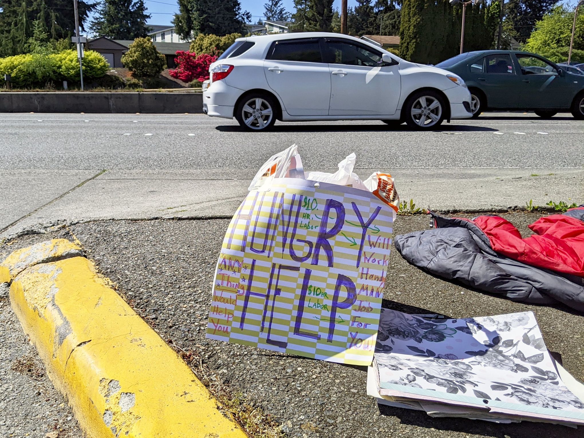 “Hungry, help,” reads a sign by Brad Peterson, 51, who advertises that he is looking for work on Highway 99 in Edmonds.