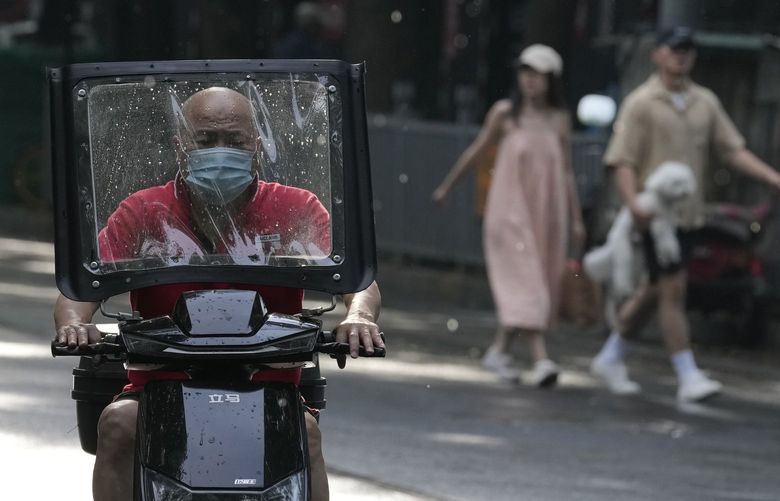 A resident wearing a mask rides a bike along a street, Tuesday, May 24, 2022, in Beijing. Beijing extended orders for workers and students to stay home and ordered additional mass testing Monday as cases of COVID-19 rose in the Chinese capital. (AP Photo/Ng Han Guan) XHG104 XHG104