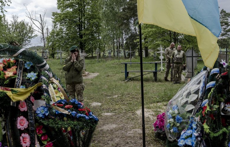 Andriy Samusenko and Anton Myahkyi’s fellow border guards lay flowers on their graves in Tykhonovychi on May 17. MUST CREDIT: Photo by Kasia Strek for The Washington Post.