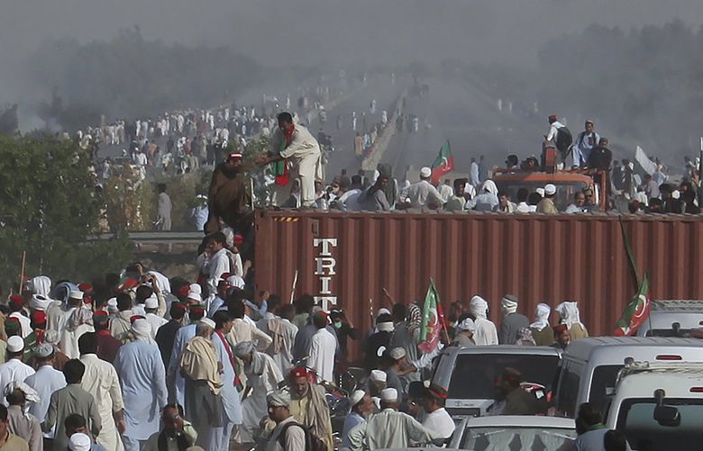 Supporters of ousted Prime Minister Imran Khan remove shipping containers placed by authorities to stop them at a highway during their march toward Islamabad, in Swabi, Pakistan, Wednesday, May 25, 2022. Pakistani police have fired tear gas and scuffled with stone-throwing supporters of Khan as they gathered for planned marches Wednesday toward central Islamabad. The defiant former premier had called followers to a rally outside Parliament to bring down the government and force early elections. (AP Photo/Mohammad Zubair) ISL132 ISL132