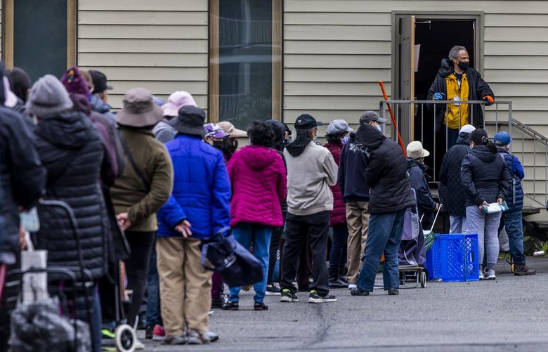 People cue up in a line waiting to receive food in-person at Rainier Valley Food Bank in Seattle on May 20, 2022. 
As a result of COVID-19 pandemic the Rainier Valley Food Bank pivoted to a home-delivery model. Recently the Rainier Valley Food Bank brought back on-site services on a limited basis.