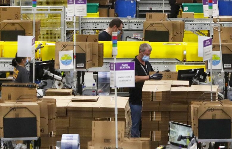 Employees at packing stations are seen at Amazon’s Kent fulfillment center, a showpiece for the company’s coronavirus response, Thursday, June 11, 2020.