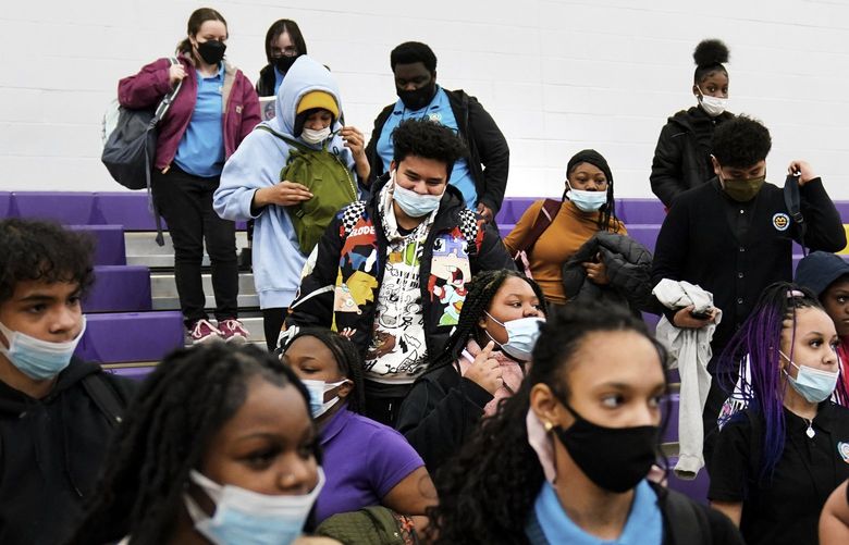 FILE – Students wearing mask as a precaution against the spread of the coronavirus line up to receive KN95 protective masks at Camden High School in Camden, N.J., Feb. 9, 2022. U.S. COVID-19 cases are up, leading a smattering of school districts, particularly in the Northeast, to bring back mask mandates and recommendations for the first time since the omicron winter surge ended and as the country approaches 1 million deaths in the pandemic. (AP Photo/Matt Rourke, File) NYAG901 NYAG901