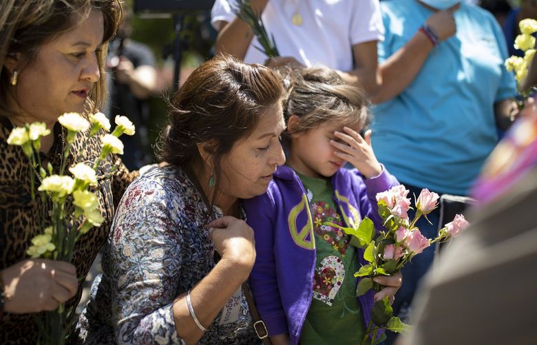 Residents say a prayer with a Texas state trooper at the entrance of Robb Elementary School in Uvalde, Texas on Wednesday, May 25, 2022. Everyone in Uvalde seemed to know one of the children who had been gunned down. Or had gone to high school with their parents or grandparents. Some had lost several family members. (Ivan Pierre Aguirre/The New York Times) XNYT180 XNYT180
