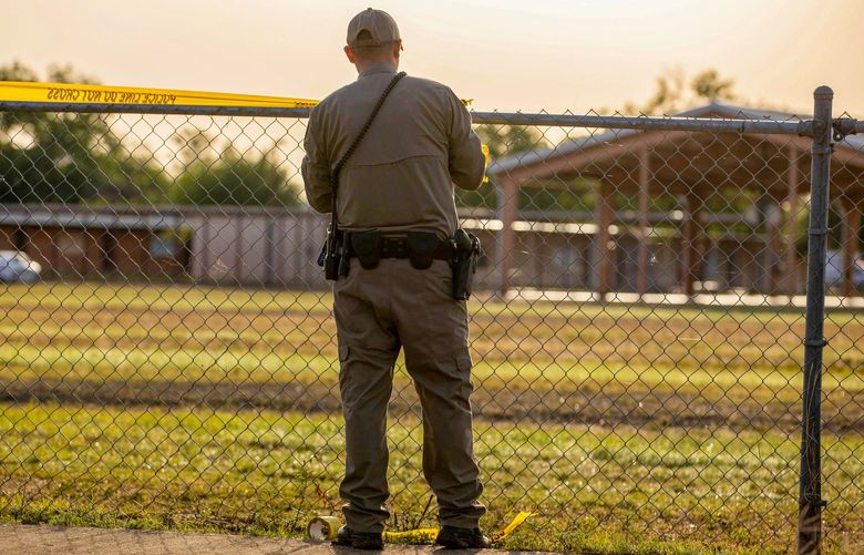 A state trooper with the Texas Highway Patrol pulls crime scene tape around a fence behind Robb Elementary School in Uvalde, Texas, on Wednesday morning, one day after a gunman killed 19 students and two teachers. Students and staff at the school participated in regular lockdown and emergency drills, as is the case in almost every American school.
