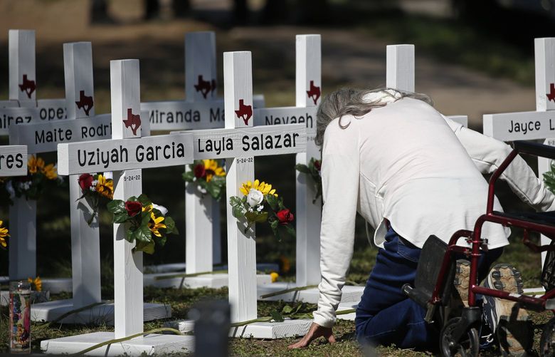 A woman kneels as she pays her respects in front of crosses with the names of children killed outside of the Robb Elementary School in Uvalde, Texas Thursday, May 26, 2022. Law enforcement authorities faced questions and criticism Thursday over how much time elapsed before they stormed the Texas elementary school classroom and put a stop to the rampage by a gunman who killed 19 children and two teachers. (AP Photo/Dario Lopez-Mills) TXDL103 TXDL103