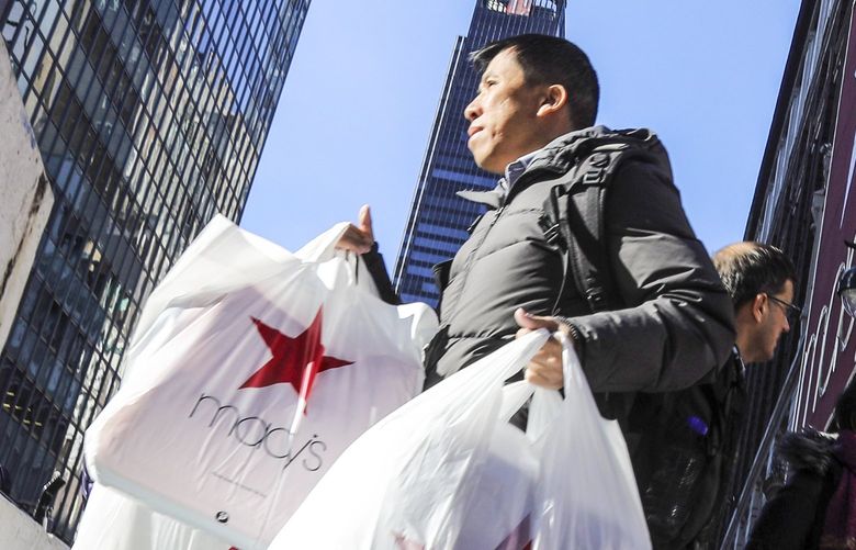 FILE – In this Nov. 29, 2019, file photo a shopper leaves Macy’s department store with bags in both hands (AP Photo/Bebeto Matthews, File) NYBZ951