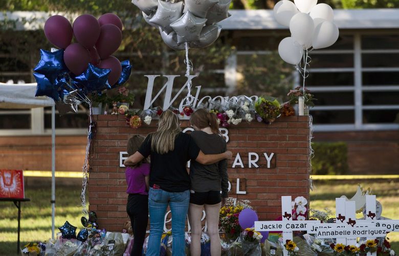 FILE – A family pays their respects next to crosses bearing the names of Tuesday’s shooting victims at Robb Elementary School in Uvalde, Texas, Thursday, May 26, 2022. (AP Photo/Jae C. Hong, File) CER904 CER904