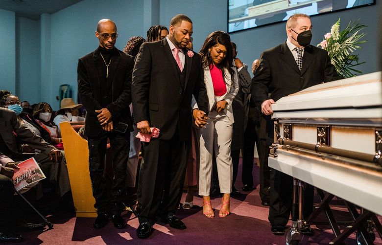 Wayne Jones and his eldest daughter, Kayla, hold hands before the casket of his mother, Celestine Chaney, one of 10 killed in the racist massacre at a grocery, in Buffalo, N.Y., May 24, 2022. Every mass shooting requires unique paths of mourning. For Chaney’s family, it meant saying farewell to a mother, sister, grandparent and best friend. (Gabriela Bhaskar/The New York Times)