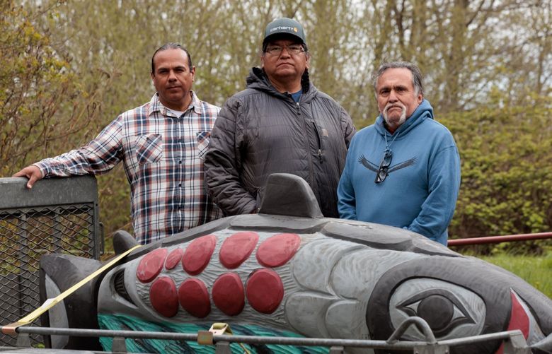 JoDe Goudy of the Yakama Nation, Lee Whiteplume of the Nez Perce Tribe, and Jewell James of the Lummi Nation stand next to a salmon that James carved as part of a totem pole meant to raise awareness of the plight of Snake River salmon and the orcas that depend on them. (Erika Schultz / The Seattle Times)
