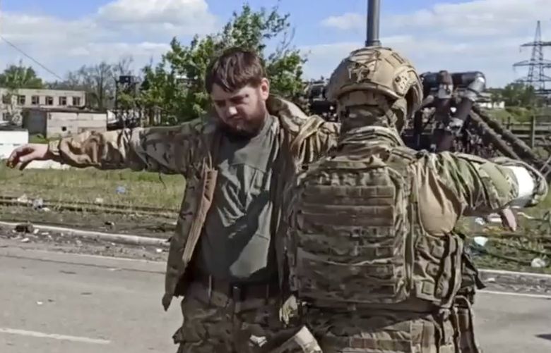 In this photo taken from video released by the Russian Defense Ministry on Friday, May 20, 2022, Russian servicemen frisk Ukrainian servicemen after they leaved the besieged Azovstal steel plant in Mariupol, in territory under the government of the Donetsk People’s Republic, eastern Ukraine. (Russian Defense Ministry Press Service via AP) MAR107 MAR107