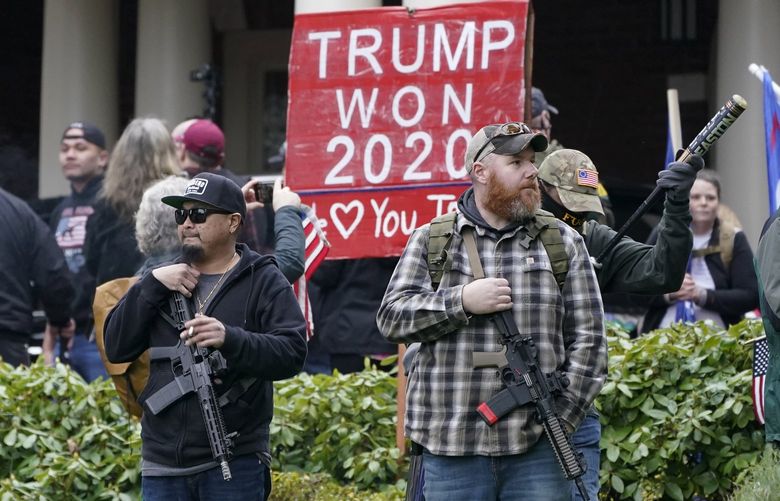 Supporters of President Trump, including those with guns and a bat, stand outside the Governor’s Mansion after breaching a perimeter fence, Wednesday, Jan. 6, 2021, at the Capitol in Olympia, Wash., following a protest against the counting of electoral votes in Washington, DC, affirming President-elect Joe Biden’s victory. The area was eventually cleared by police. (AP Photo/Ted S. Warren)