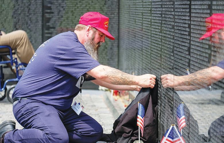 Bruce Hansen of Marysville lays a jacket that belonged to his father, Vietnam War veteran David Hansen, at the Vietnam Veterans Memorial in Washington, D.C., during a visit organized by Inland Northwest Honor Flight on April 26, 2022. David Hansen, who was scheduled to join an Honor Flight trip two years earlier that was delayed by the COVID-19 pandemic, died in February 2022.