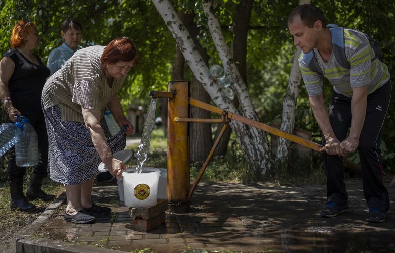 Residents gather to collect water from a pump in the street in Sloviansk, Ukraine, on Thursday, June 2, 2022. In towns and cities near the fighting in eastern Ukraine, artillery and missile strikes have downed power lines and punched through water pipes, leaving many without electricity or water as repair crews race to repair the damage. (AP Photo/Elena Becatoros) BA101 BA101