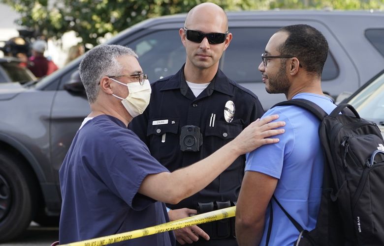 Hospital staff talk to a Los Angeles Police officer after a suspect who stabbed multiple people remained barricaded inside the Encino Hospital Medical Center in Encino, Calif., Friday, June 3, 2022. After a standoff, the suspect was taken into custody and into an ambulance. (AP Photo/Damian Dovarganes) CADD503 CADD503