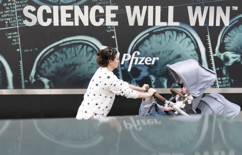 A woman pushes a baby in a stroller past a sign hanging outside Pfizer headquarters in New York, Monday, May 23, 2022. Three doses of Pfizer’s COVID-19 vaccine offer strong protection for children younger than 5, the company announced Monday, May 23, 2022. Pfizer plans to give the data to U.S. regulators later this week in a step toward letting the littlest kids get the shots. (AP Photo/Mary Altaffer) NYMA106 NYMA106