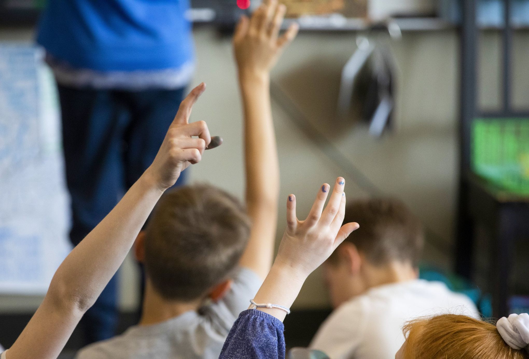 Students raise hands during class at Woodridge Elementary School in Bellevue.