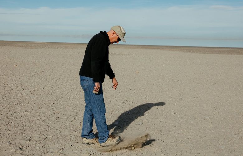 Kevin Perry, a professor of atmospheric studies at the University of Utah, walks on land that used to be submerged by the Great Salt Lake in Utah, March 15, 2022. Climate change and rapid population growth are shrinking the lake, creating a bowl of toxic dust that could poison the air around Salt Lake City. (Bryan Tarnowski/The New York Times)