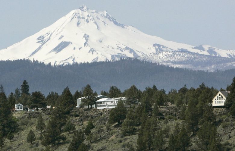FILE – Mount Jefferson looms over off-grid homes at the Three Rivers Recreational Area, in Lake Billy Chinook, Ore., on April 26, 2007. Everyone in this community lives “off the grid”, part of a growing number of homeowners now drawing all their power from solar, wind, propane and other sources. (AP Photo/Don Ryan, File) NYCL306 NYCL306