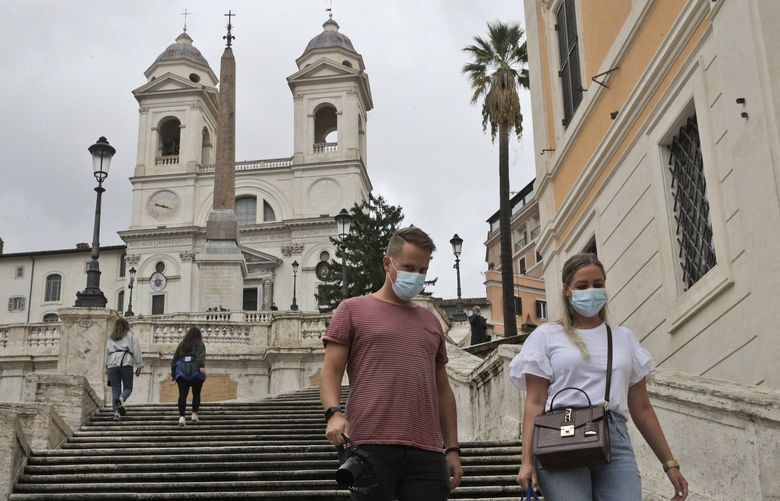A couple wearing face mask to stop the spread of COVID-19, descends the Spanish Steps in Rome, Tuesday, Oct. 6, 2020. Italy’s health minister said that the government is examining a proposal to make masks mandatory outdoors as the country enters a difficult phase of living alongside COVID-19 with the number of infections growing steadily for the last nine weeks. (AP Photo/Gregorio Borgia)