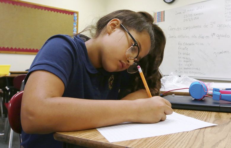 Fourth grade Spanish/English dual language class student Jaqueline Powell, 10, writes her assignment in Spanish at the New Mexico International School in Albuquerque, N.M., on Monday, May 23, 2022. (AP Photo/Cedar Attanasio) NMCA104 NMCA104
