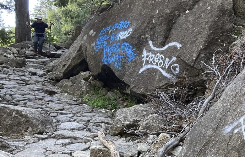 In this photo released, Sunday June 12, 2022, by the National Park Service, a hiker walks down a graffiti covered trail in Yosemite National Park, Calif. (National Park Service via AP) FX106 FX106