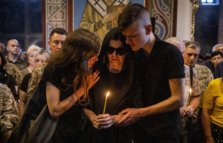 Olena Prymachenko, center, is comforted by family members during the funeral service for her husband, Volodymyr Prymachenko, at St. Michaels Monastery in Kyiv, Ukraine on June 14, 2022. A veteran of the war in Afghanistan, Prymachenko was killed on June 5, 2022 near Bakhmut in the Donetsk region of Ukraine. (Ivor Prickett/The New York Times) XNYT57 XNYT57