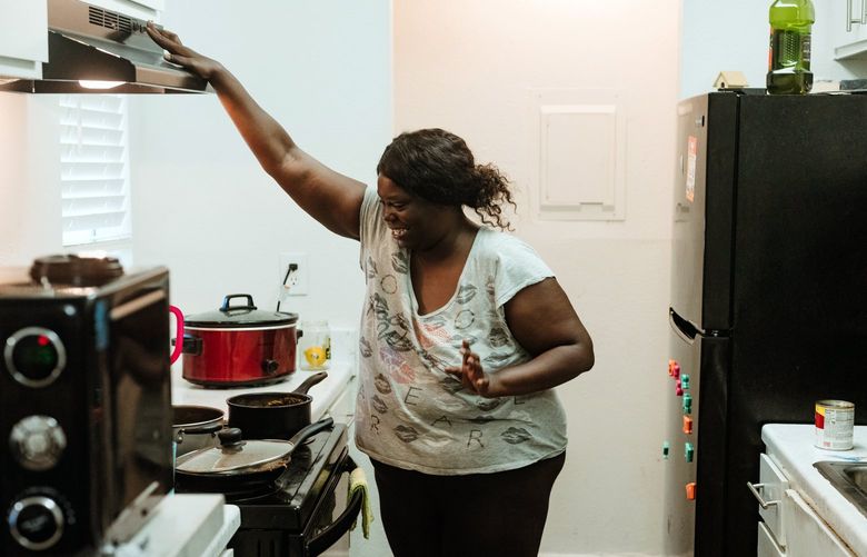 Terri Harris, a formerly homeless woman who received a lease for a one-bedroom in a low-rise complex, prepares a meal at the new home she shares with her daughter Blesit in Houston on May 12, 2022. Harris did not score high enough on a “vulnerability index” to be eligible for permanent housing, but she did qualify for what is called rapid rehousing, which gave her one year of rent – one year of grace – to get back on her feet.  (Christopher Lee/The New York Times)