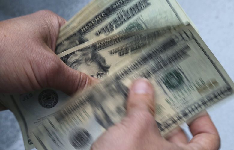 FILE- In this June 15, 2018, file photo, twenty dollar bills are counted in North Andover, Mass.  Photo/Elise Amendola, File) 