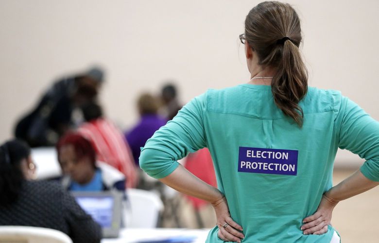 FILE – In this Nov. 8, 2016, file photo, poll watcher Jane Grimes Meneely, right, watches as voters sign in at the Martha O’Bryan Center community building in Nashville, Tenn. (AP Photo/Mark Humphrey, File)