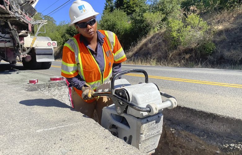Jasmin Hardy, with a PG&E crew, works at installing underground power lines along Porter Creek Road in Sonoma County, Calif., site of the 2017 Tubbs Fire, on Monday, June 13, 2022. Pacific Gas & Electric Co. has started an ambitious project to bury underground thousands of miles of power lines in an effort to prevent igniting fires with its equipment and avoid shutting down power during hot and windy weather. (AP Photo/Haven Daley) FX403 FX403