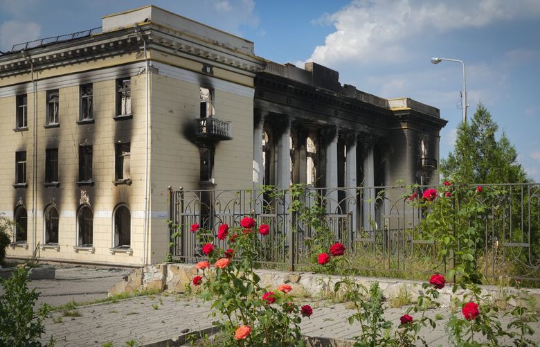 Red roses are seen against the background of a city theatre ruined in the Russian shelling in Lysychansk, Luhansk region, Ukraine, Thursday, June 16, 2022. (AP Photo/Efrem Lukatsky) XEL117 XEL117